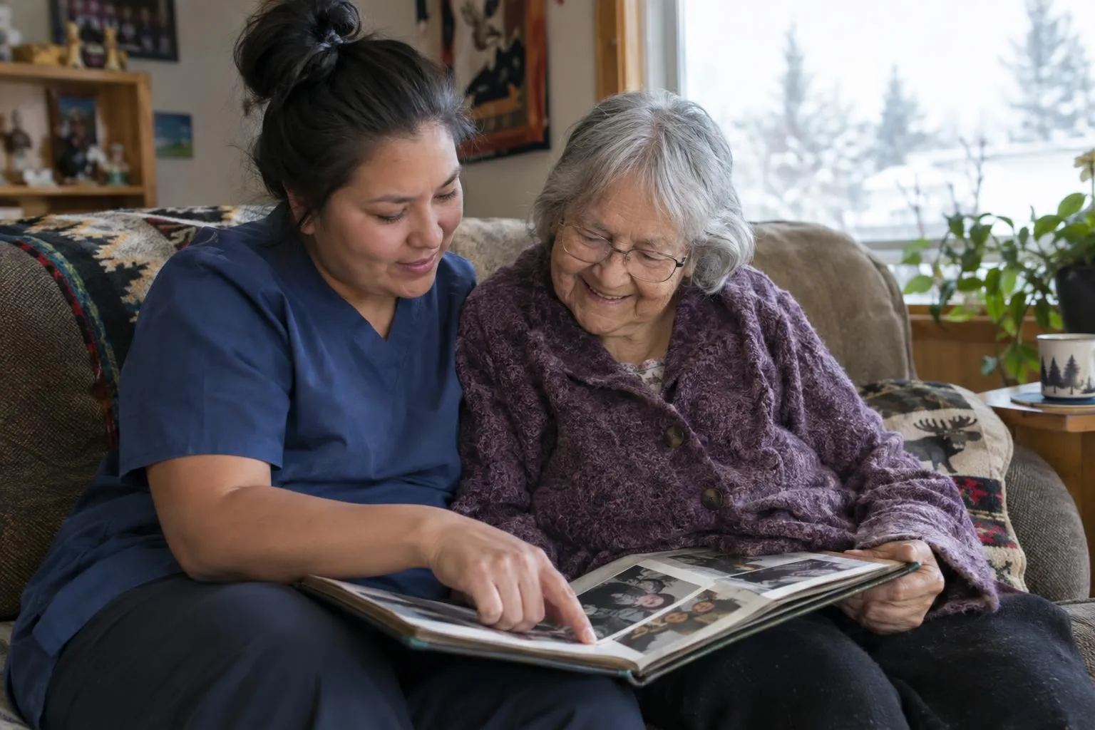 A caregiver and an older woman look through a family photo album together on the sofa.