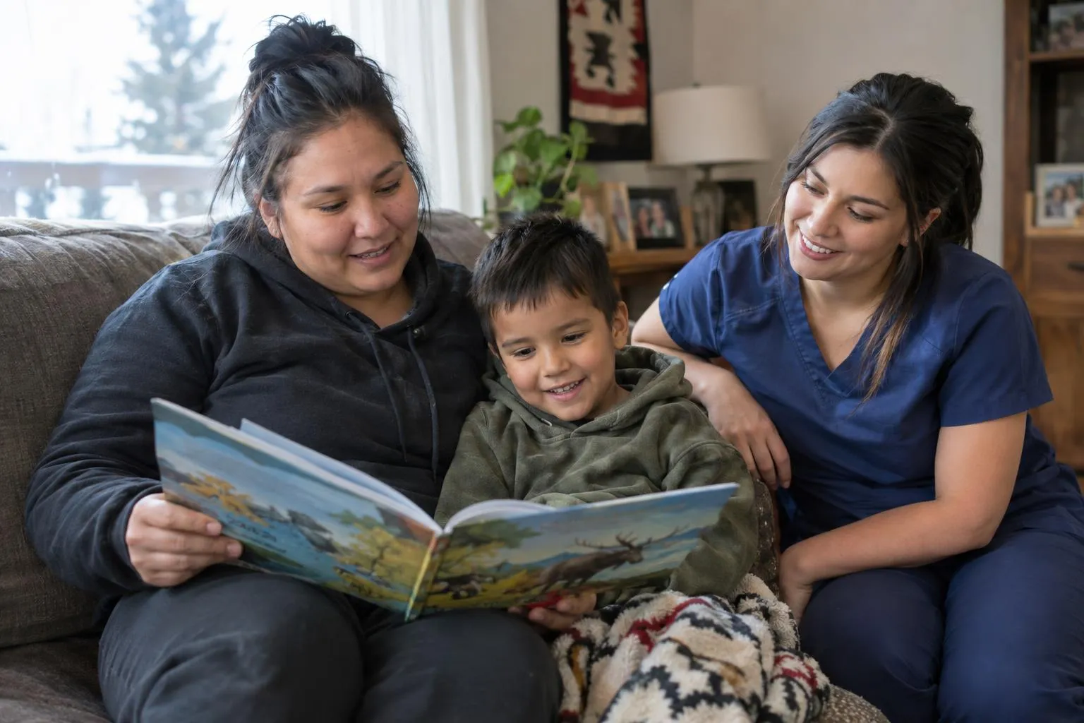 A foster mother reads with a young boy on the couch while a support worker kneels beside them.