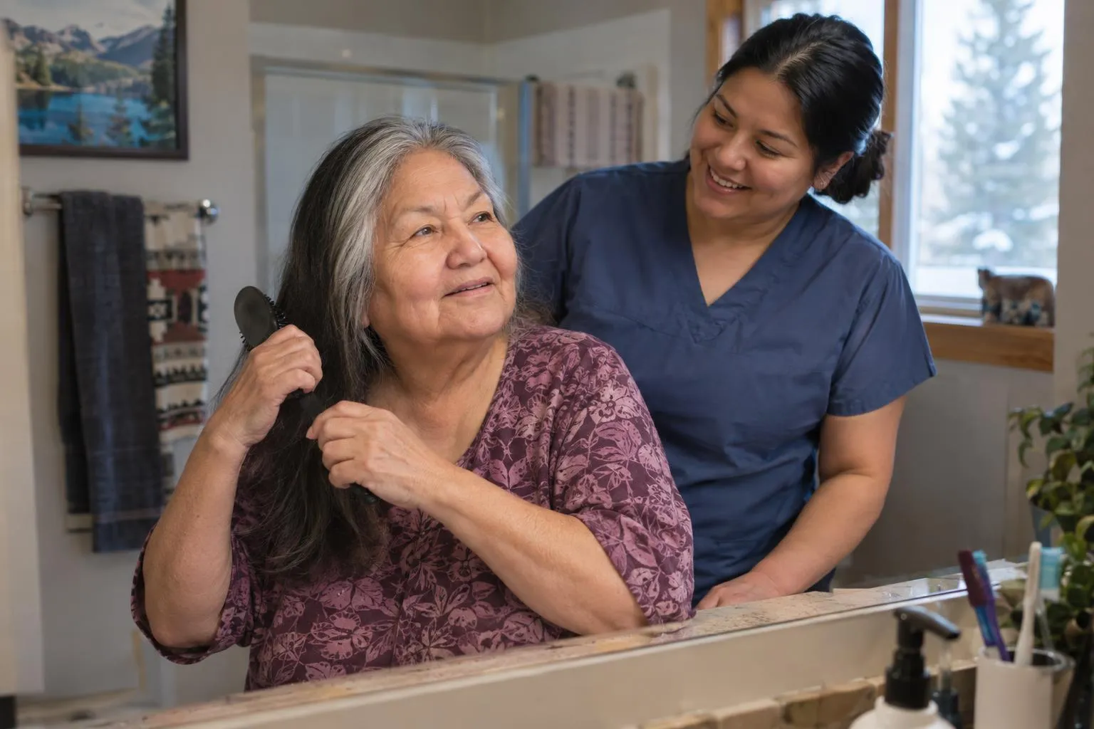 An older woman brushes her hair at the mirror while a care worker stands nearby.