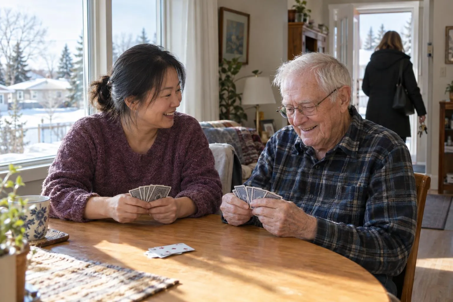 A caregiver plays cards with an older man while his daughter heads out for a break.